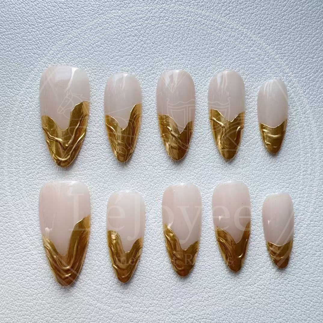 A minimalist luxury aesthetic shot of the nude and gold nails against a soft white silk fabric, emphasizing the "Old Money" vibe.