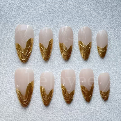 A minimalist luxury aesthetic shot of the nude and gold nails against a soft white silk fabric, emphasizing the "Old Money" vibe.