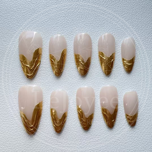 A minimalist luxury aesthetic shot of the nude and gold nails against a soft white silk fabric, emphasizing the "Old Money" vibe.