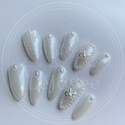 Luxury handmade press-on nails "Moonlit Ballet" featuring a lustrous white pearl chrome finish, accented with a silver metallic bow and a delicate micro-pearl frame.