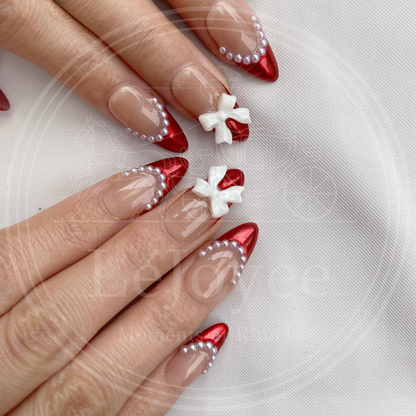 Hand model wearing the "Rouge Coquette" nail set, embodying the trendy coquette aesthetic with a mix of bold red and sweet feminine details.