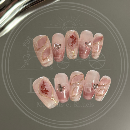 Shot of delicate pink rhinestone butterfly embellishments and gold-outlined abstract leaf patterns on glossy press-on nails.