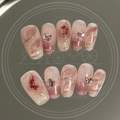 Luxury handmade press-on nails "Antique Rose" featuring a dusty pink cat-eye base, gold wire-framed petal art, and rhinestone butterfly charms.
