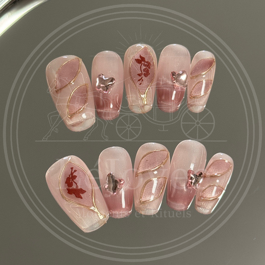 Luxury handmade press-on nails "Antique Rose" featuring a dusty pink cat-eye base, gold wire-framed petal art, and rhinestone butterfly charms.