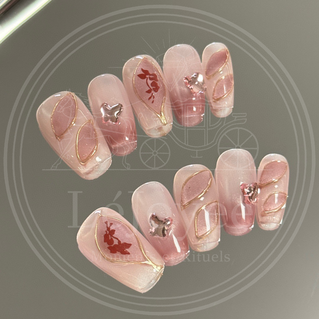 A full set of "Antique Rose" press-on nails displayed on a reflective surface, highlighting the soft gradient and vintage romantic aesthetic.