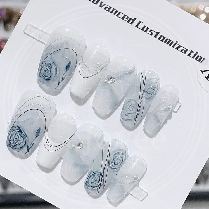 Luxury handmade press-on nails "Azure Sketch" featuring a milky white base with hand-painted blue ink-wash roses and abstract black line art.