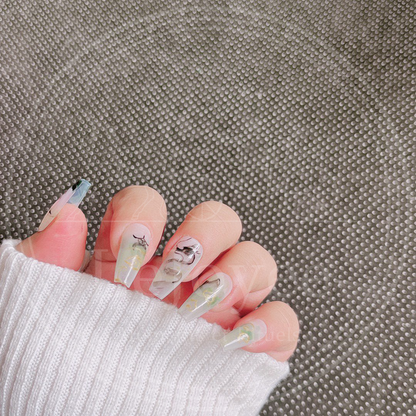 Artistic flatlay of the custom press-on nail set, highlighting the translucent sheer base and the fluidity of the black ink brushstrokes against the gold details.