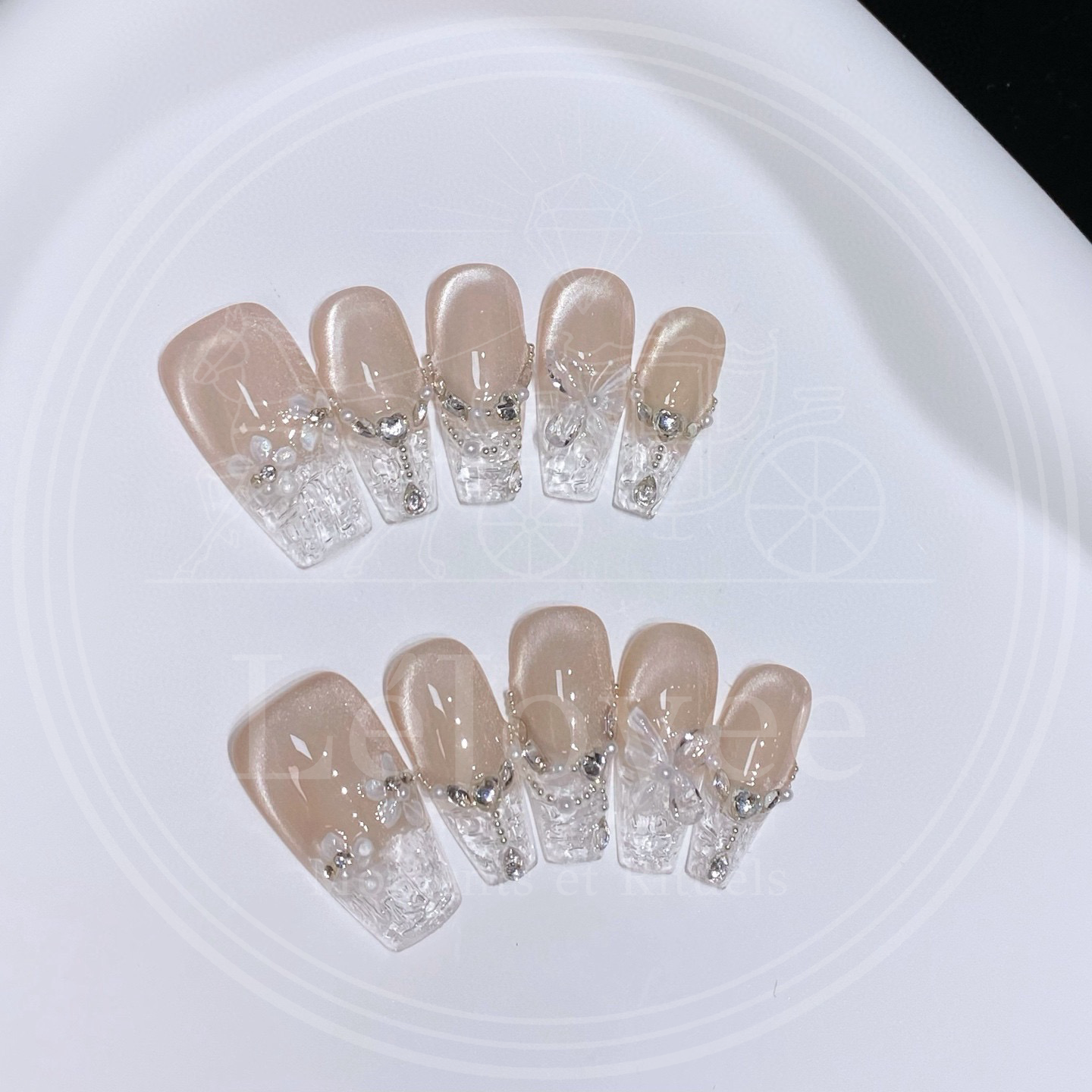 Close-up of translucent butterfly charms and draped silver chains with micro-pearls on a set of elegant coffin-shaped Glass Serenade wedding nails.