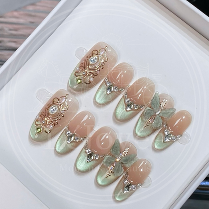 Luxury handmade press-on nails "Sage Baroque" featuring soft sage green magnetic cat-eye tips, intricate gold-coloured baroque relief art, and 3D butterfly charms