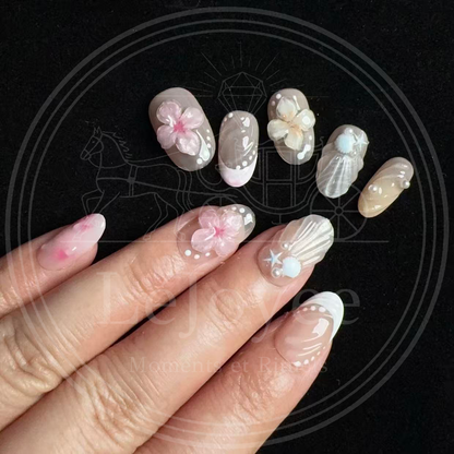 Macro shot highlighting the pearlescent ridged seashell texture, tiny pearl accents, and miniature starfish gems on the beach-themed accent nails.