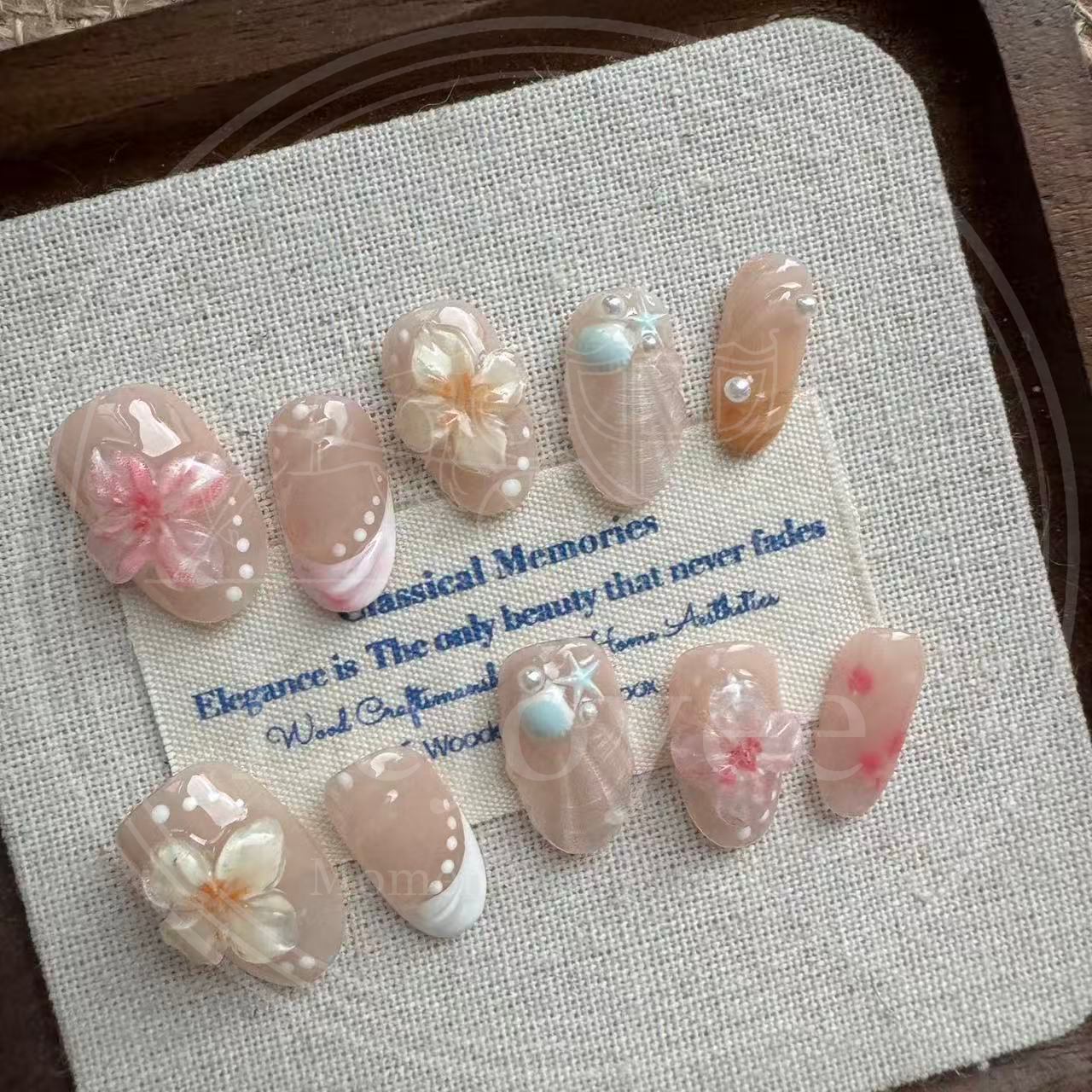 Handmade short squoval press-on nails "Sakura Shores" featuring translucent 3D pink and yellow jelly sakura flowers, textured shell designs, and blush gradients on a nude base.