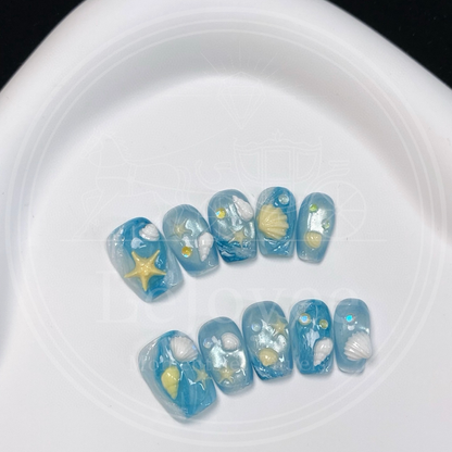 Top-down view of the summer-themed nail set, highlighting the realistic sea spray bubbles and swirling wave textures resembling a beach shoreline.