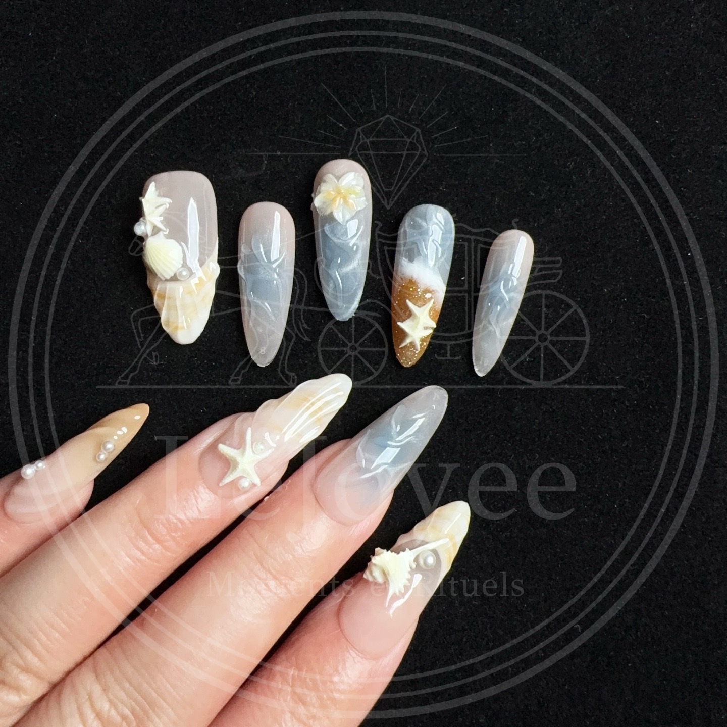 Summer beach nail design details including white starfish charms and tiny pearls placed on translucent water-ripple effect nails.