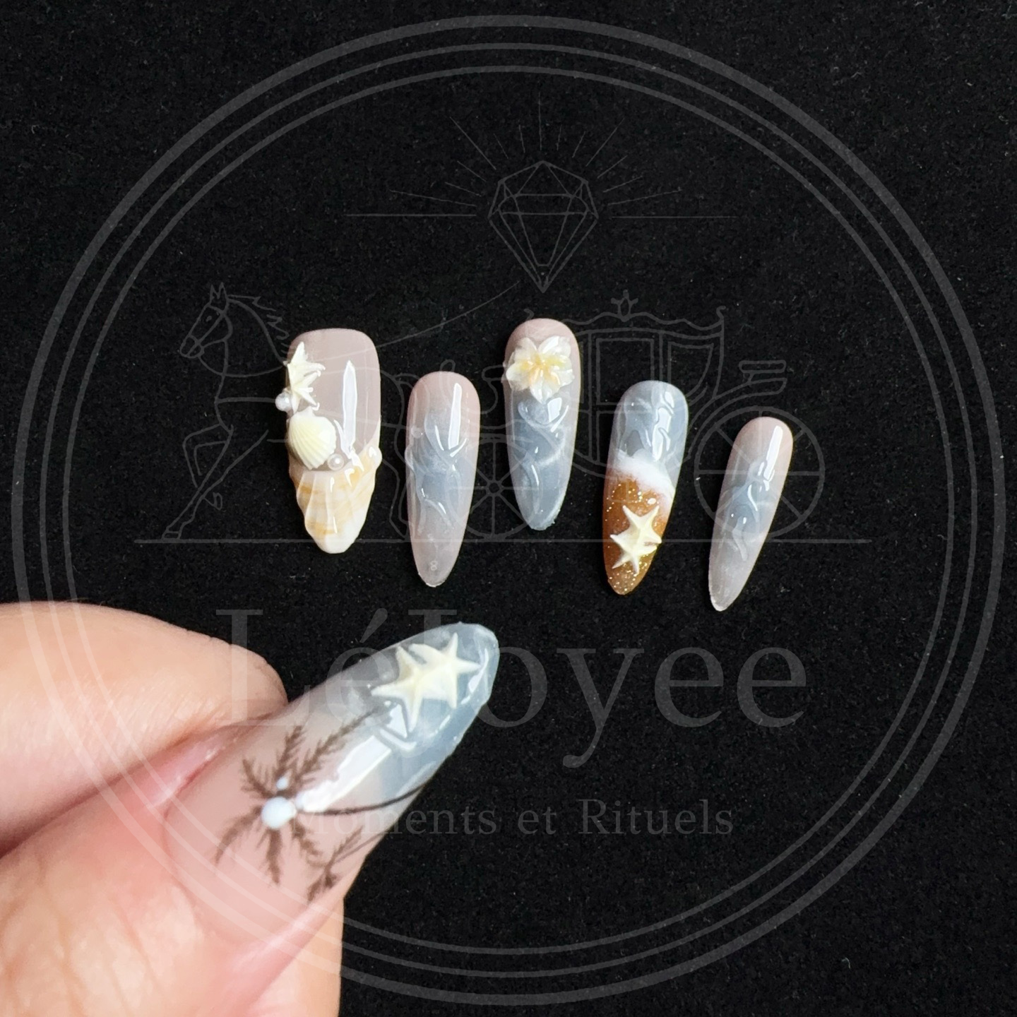 Close-up of a black palm tree silhouette against a shimmering blue-grey ocean background on a long almond press-on nail.