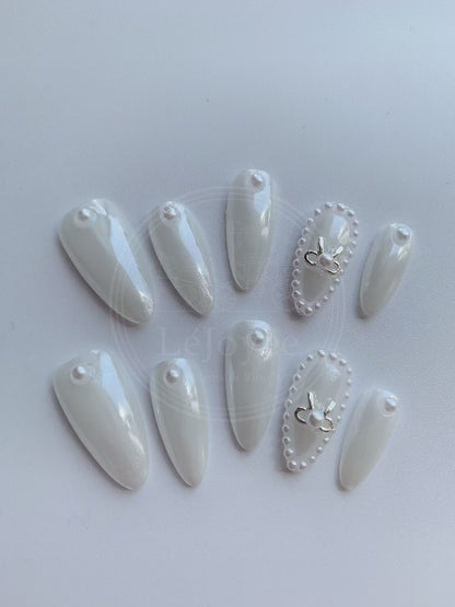 Video capturing the soft, satin-like sheen of the pearl white polish and the cool reflection of the silver ribbon charm on the Moonlit Ballet nail set.