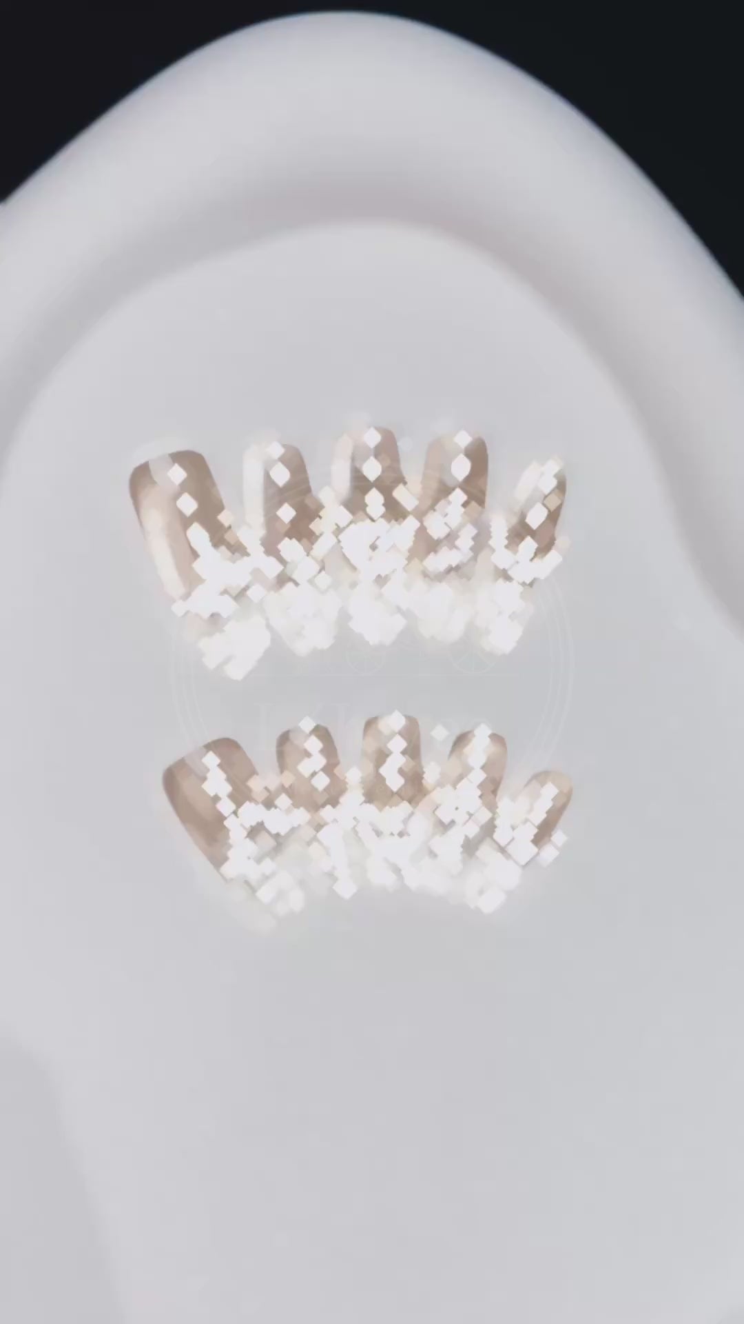 Video showcasing the light passing through the clear "crushed ice" french tips and the shimmer of the pearl details on the Glass Serenade press-ons.