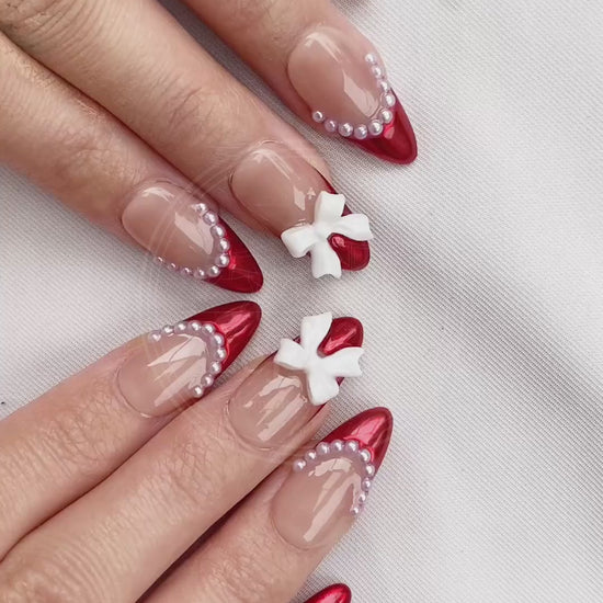 Video showcasing the dynamic shimmer of the metallic red tips and the cute dimension of the white bows on the Rouge Coquette nails in motion