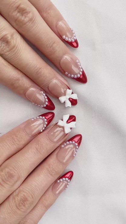 Video showcasing the dynamic shimmer of the metallic red tips and the cute dimension of the white bows on the Rouge Coquette nails in motion